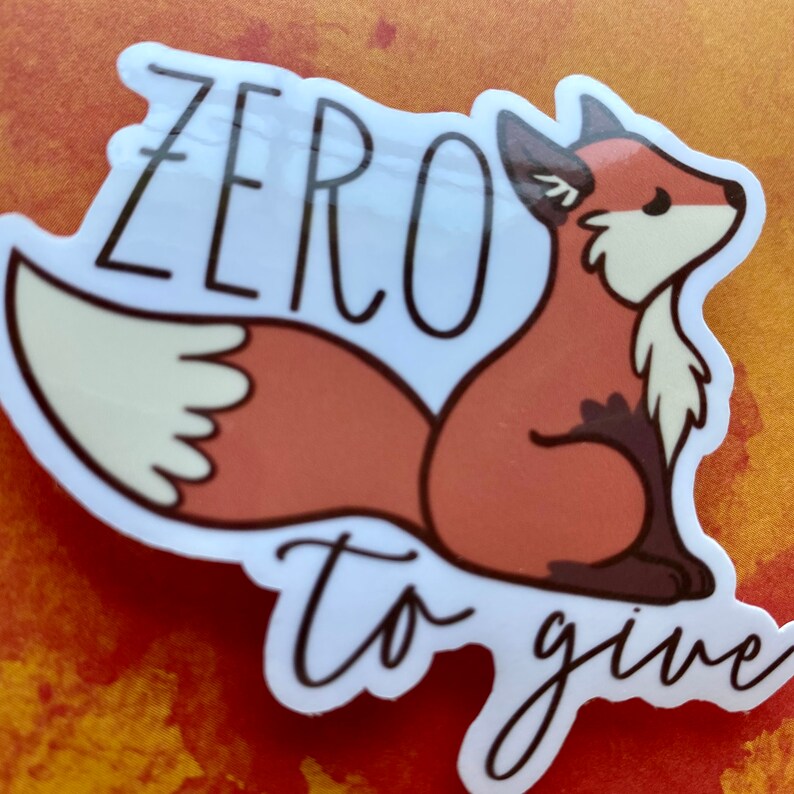 May include: A white sticker with a cartoon fox with a bushy tail. The fox is sitting down and looking to the right. The text "zero to give" is written in black cursive script.