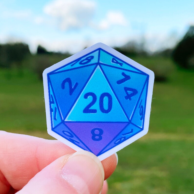 May include: A blue and purple 20-sided die sticker with white numbers. The sticker is shaped like a die and has a gradient of blue and purple colours.