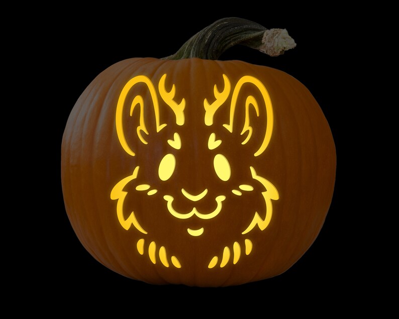 May include: A carved pumpkin with a cute, stylized animal face. The animal has large eyes, a small nose, and antlers. The pumpkin is lit from inside, creating a warm glow.