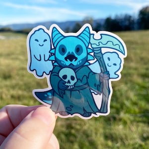 May include: A blue and green cartoon dragon wearing a hooded robe and holding a skull. The dragon is surrounded by two white ghosts. The dragon is holding a scythe in its right hand.