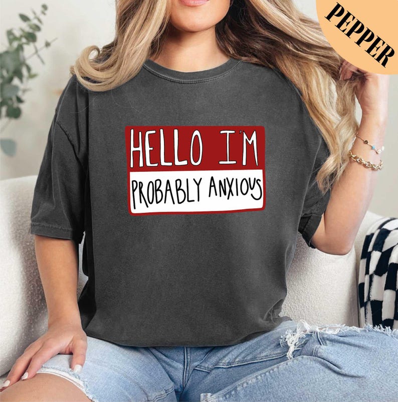 a woman sitting on a couch wearing a black shirt with the words hello i '