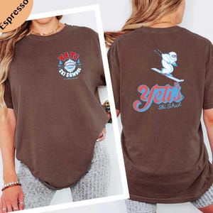 a woman wearing a brown t-shirt with a graphic design on the back.