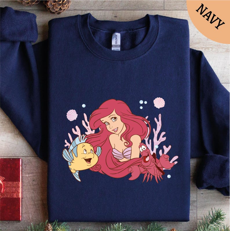 a blue shirt with a little mermaid and a fish on it