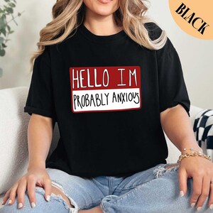 a woman sitting on a couch wearing a black shirt
