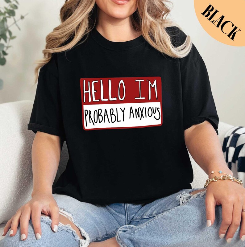 a woman sitting on a couch wearing a black shirt