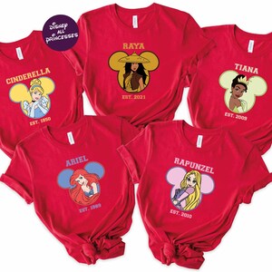 A collection of red t-shirts featuring Disney princesses, including Cinderella, Ariel, Rapunzel, and Tiana.