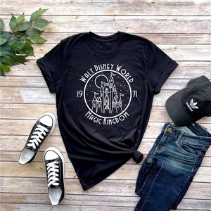 K&ouml;nnte beinhalten: Schwarzes T-Shirt mit einer wei&szlig;en Grafik von Schloss Aschenputtel in einem Kreis mit dem Text "Walt Disney World 1971 Magic Kingdom".