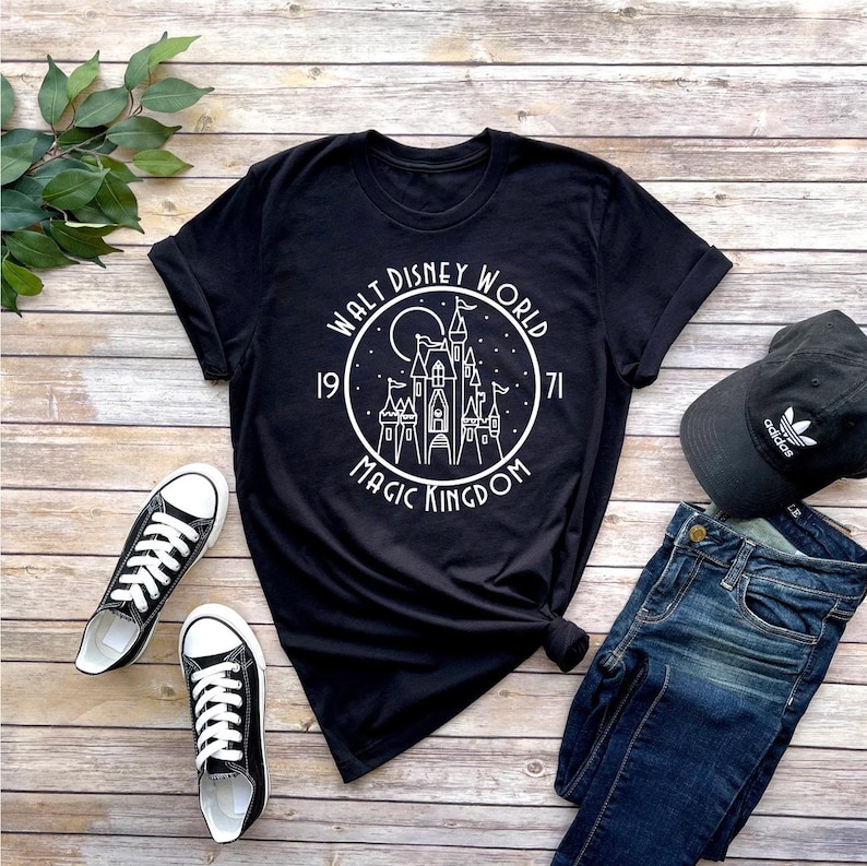 K&ouml;nnte beinhalten: Schwarzes T-Shirt mit einer wei&szlig;en Grafik von Schloss Aschenputtel in einem Kreis mit dem Text "Walt Disney World 1971 Magic Kingdom".