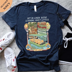 A navy blue t-shirt with a colorful graphic design and text, along with a pair of white sneakers and a black belt.