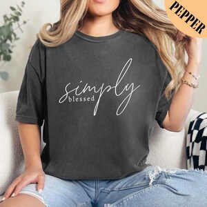 a woman sitting on a couch wearing a black simply shirt