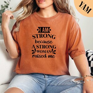 a woman sitting on a couch wearing a brown shirt