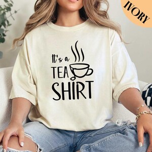 a woman sitting on a couch wearing a t - shirt that says it's