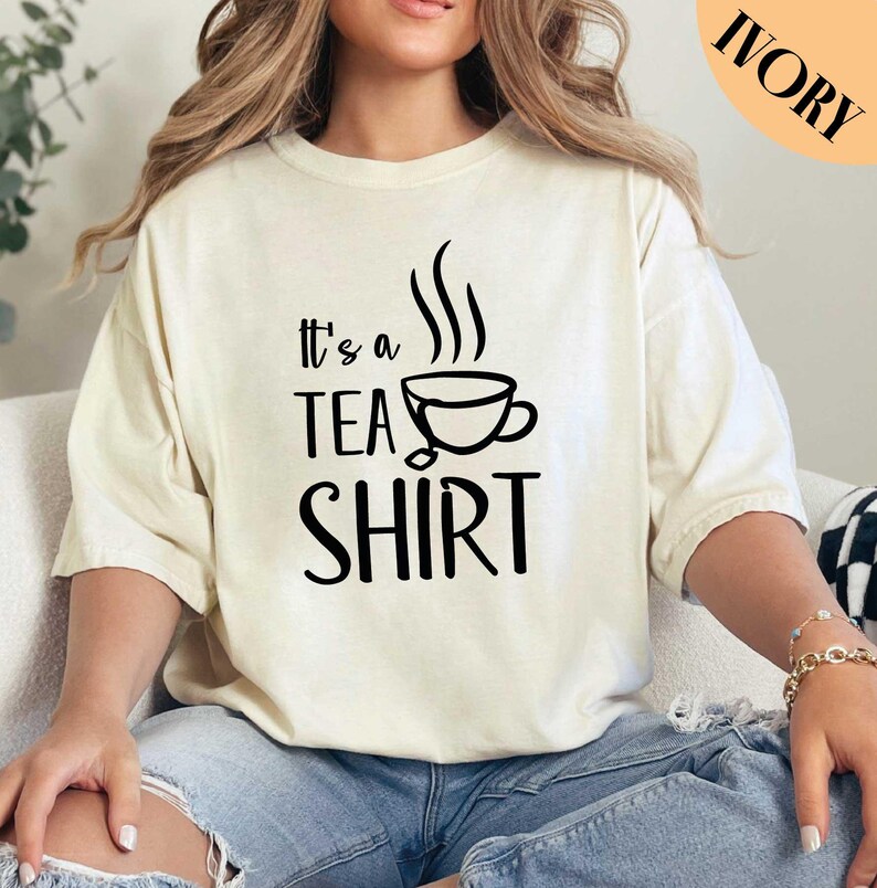 a woman sitting on a couch wearing a t - shirt that says it's