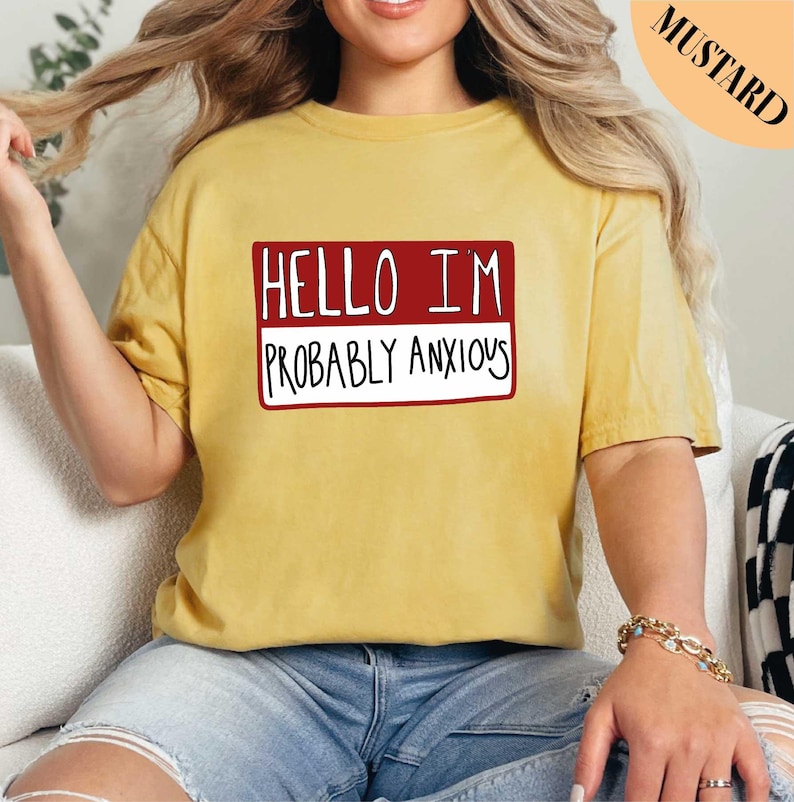 a woman sitting on a couch wearing a pink shirt that says hello i'm