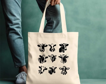 May include: A white canvas tote bag with black silhouettes of cow heads. The bag features nine different cow head designs, each with unique markings and expressions.