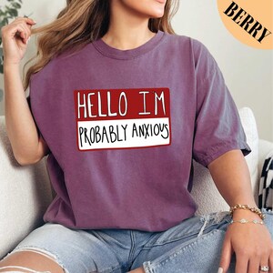 a woman sitting on a couch wearing a t - shirt that says hello im probably