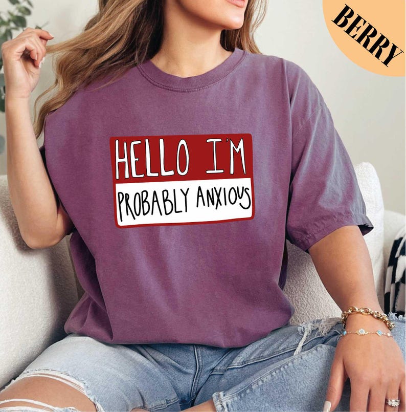 a woman sitting on a couch wearing a t - shirt that says hello im probably