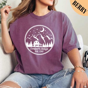 a woman sitting on a couch wearing a purple shirt
