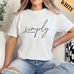 a woman sitting on a couch wearing a white simply t - shirt