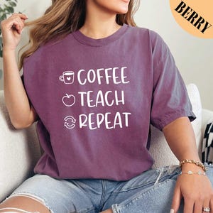May include: A purple t-shirt with the text "Coffee Teach Repeat" in white. The text is in a checklist format with a coffee cup, apple, and a circular arrow next to each item.