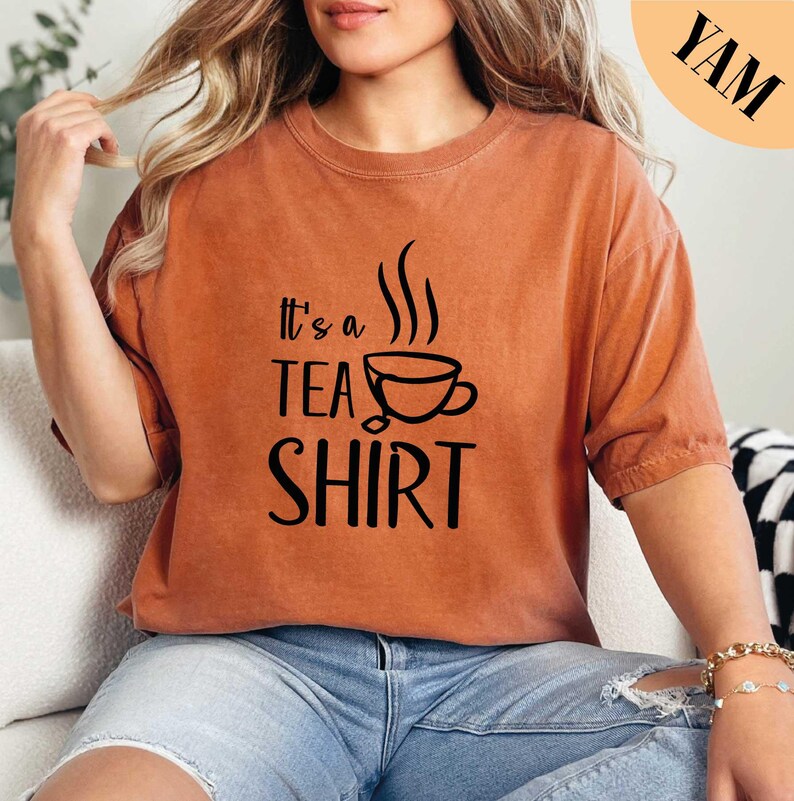 a woman sitting on a couch wearing a t - shirt that says it's