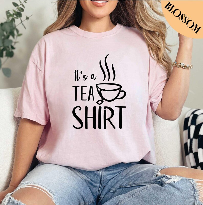 a woman sitting on a couch wearing a pink shirt that says it's a