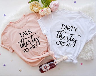 May include: Two t-shirts with text on them. One is pink and says "Talk thirty to me". The other is white and says "Dirty thirty crew".