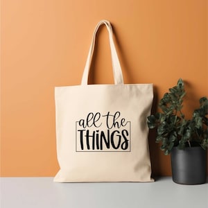 May include: A white canvas tote bag with black text that reads "all the THINGS" in a handwritten font.
