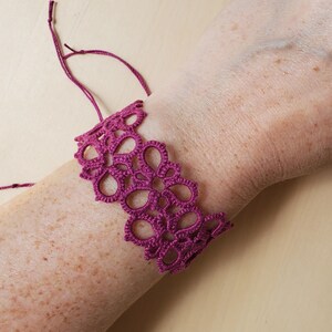 May include: A deep purple crocheted bracelet with a delicate floral pattern.