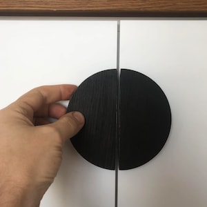 Può includere: Maniglie per porte di armadio in legno nero a forma di semicircolo. Le maniglie sono composte da due pezzi che si incastrano per formare un cerchio.
