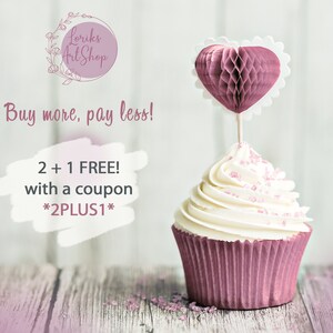 May include: A pink cupcake with white frosting and pink sprinkles topped with a pink honeycomb heart. The cupcake is sitting on a wooden surface. The text "Buy more, pay less! 2 + 1 FREE! with a coupon *2PLUS1*" is written on a white background.