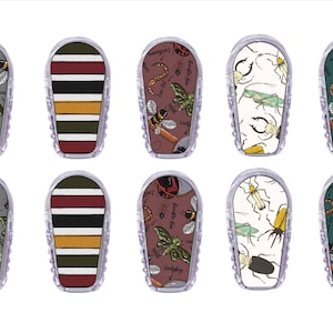 May include: Ten clear, plastic, rectangular shaped items with various designs. Some have insect patterns, others have striped patterns in red, yellow, and black. The insect designs include bees, moths, and ladybugs.