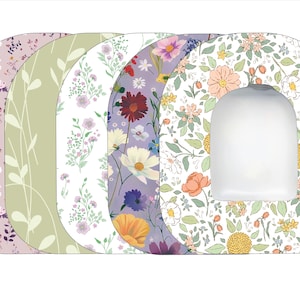 May include: Set of five floral patterned toilet seat covers. The covers are in various shades of pink, green, purple, and white. Each cover features a different floral design.