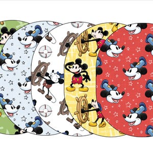 May include: Four round fabric placemats with a nautical theme featuring Mickey Mouse in different poses. The placemats are green, blue, white, and red with a variety of patterns including stars, anchors, and ship wheels.