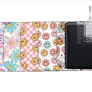 May include: Five different patterned phone cases with a black phone case with a clear top and a small tube attached to the top. The phone cases feature a variety of patterns including pink and white checkered, white with pink flowers, white with smiley faces, and blue and white stripes.