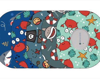 Könnte beinhalten: Fünf verschiedene farbige Klebepatches für einen kontinuierlichen Glukosemonitor (CGM) mit verschiedenen Meeresmotiven, darunter Haie, Krabben, Muscheln und ein Piratenschiff. Die Patches sind für die Verwendung mit einem Dexcom CGM konzipiert.