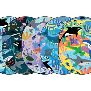 May include: Five colorful round fabric placemats with a variety of sea creatures, including sharks, whales, stingrays, and seahorses. The placemats are decorated with a blue, green, orange, yellow, and purple background.