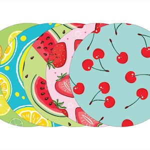 May include: Four round coasters with different fruit designs. The coasters are green, blue, pink, and light blue with watermelon, lemons, strawberries, and cherries.