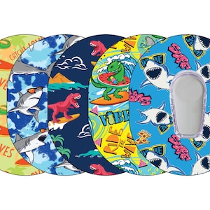 May include: A collection of colorful, patterned medical device covers. Designs include dinosaurs and sharks surfing, with text that reads "Catch the Waves" and "Vibe". The covers are in shades of blue, green, and yellow.