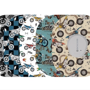 May include: A collection of patterned medical device covers featuring motocross bike designs. The covers display various color schemes, including gray, blue, and tan, with illustrations of motorcycles, helmets, and riders. A white device is visible on the right side.