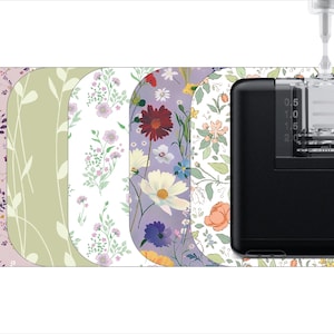 May include: A black and clear medical device with a floral patterned skin. The device has a clear reservoir and a scale marked in 0.5 increments. The device is being filled with liquid from a clear tube.