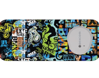 Puede incluir: Una pegatina rectangular con temática BMX. El diseño presenta ciclistas de BMX, texto estilo grafiti y un objeto circular gris con el texto "dexcom". Los colores incluyen negro, azul, verde y naranja.