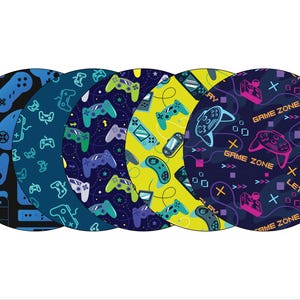 May include: Five round coasters with a blue, yellow, and black background. The coasters feature a repeating pattern of video game controllers and the text "GAME ZONE" and "LET'S PLAY".