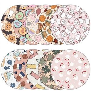 May include: A collection of round coasters with various patterns. Designs include Halloween pumpkins and bats, candy hearts, cakes, pumpkins, turkeys, snowmen, candy canes, Easter bunnies, shamrocks, and Santa faces. The coasters are in shades of orange, pink, and green.