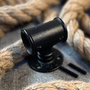 May include: Black metal pipe fitting with a round base and a threaded opening. The fitting is surrounded by natural rope.