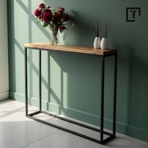 Op de afbeelding: Een moderne console met een licht houten blad en een zwart metalen frame. De tafel heeft een rechthoekig ontwerp. Een vaas met rode bloemen en twee witte vazen met riet staan erop.