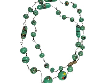 May include: A handmade necklace featuring a series of turquoise glass beads in various shapes and sizes. The beads are strung on a dark wire, with some beads displaying colorful, speckled patterns. The necklace has a unique, artistic design.