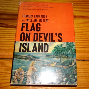 May include: A vintage book titled "Flag on Devil's Island" by Francis Lagrange and William Murray. The cover is orange with black and white text and a colorful illustration of an island scene.
