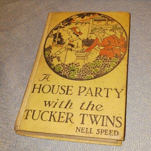 Può includere: Un libro d'epoca ingiallito, "A House Party with the Tucker Twins" di Nell Speed. La copertina presenta un'illustrazione di persone in un giardino. Il titolo è stampato in lettere scure.