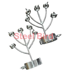 Pode incluir: Duas algemas de metal prateado com um design ramificado, cada uma com múltiplos componentes circulares. O texto "Steel Bird" é parcialmente visível em vermelho. As algemas têm um acabamento polido.